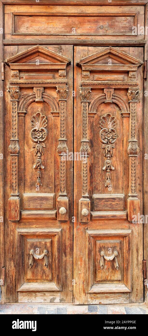 Antiguas puertas de entrada de madera con elementos tallados enmarcados en  la fachada con un patrón simétrico tallado de arriba a abajo Fotografía de  stock - Alamy