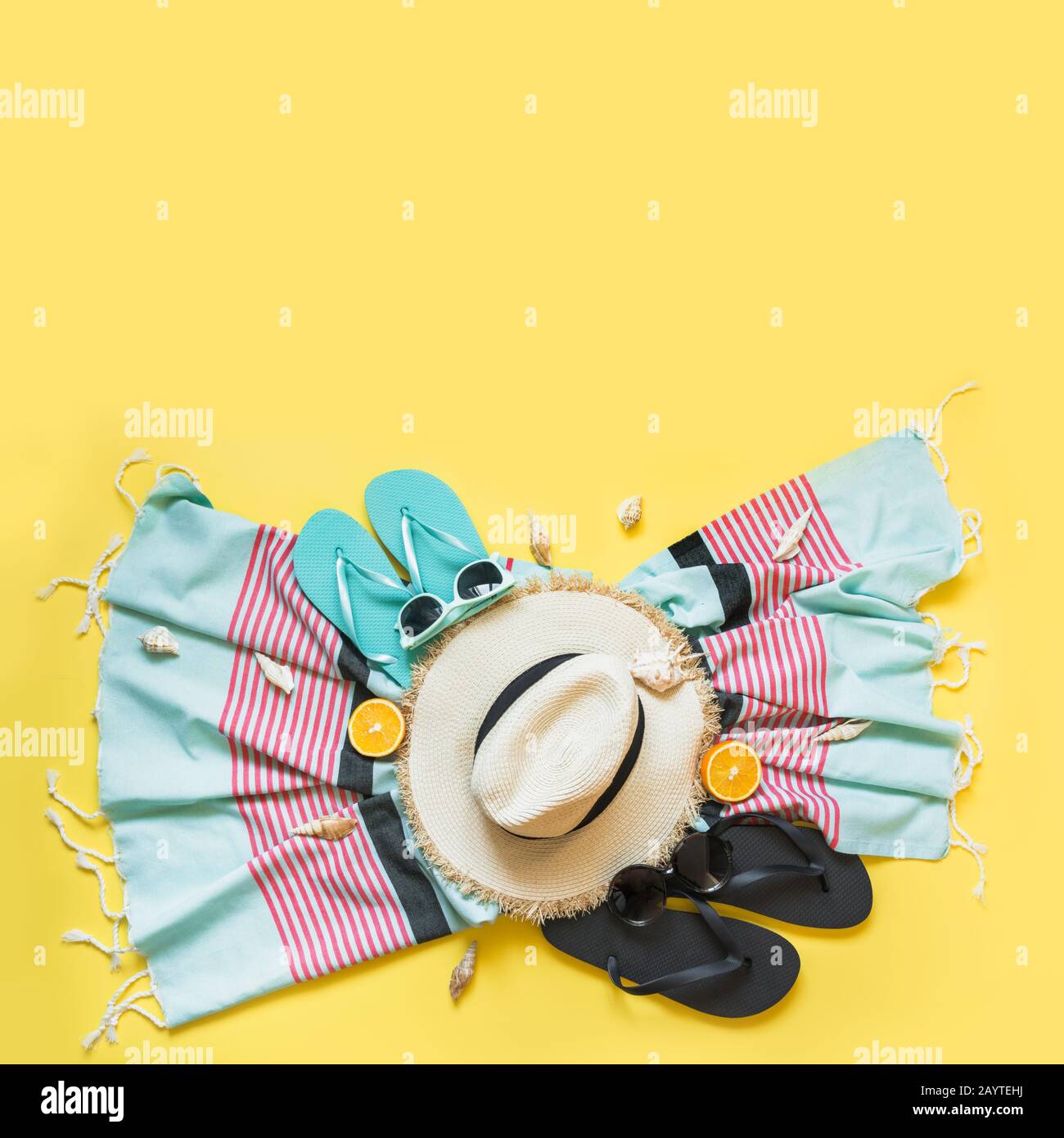 Conjunto para vacaciones tropicales en la playa, sombrero de paja, toalla, gafas de sol en amarillo. Concepto de verano. Vista superior. Espacio para texto. Foto de stock