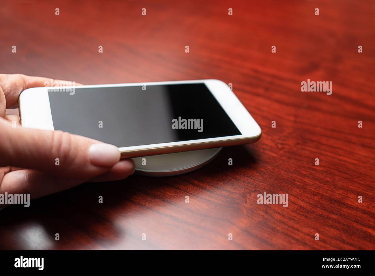 Con la mano se puede guardar un smartphone móvil para cargarlo de forma inalámbrica compartiendo la batería a través del dispositivo. Tecnología de carga. Uso Compartido De Carga De Dispositivos Técnicos. Nueva tecnología, transferencia de electricidad sin cables. Primer plano. Foto de stock