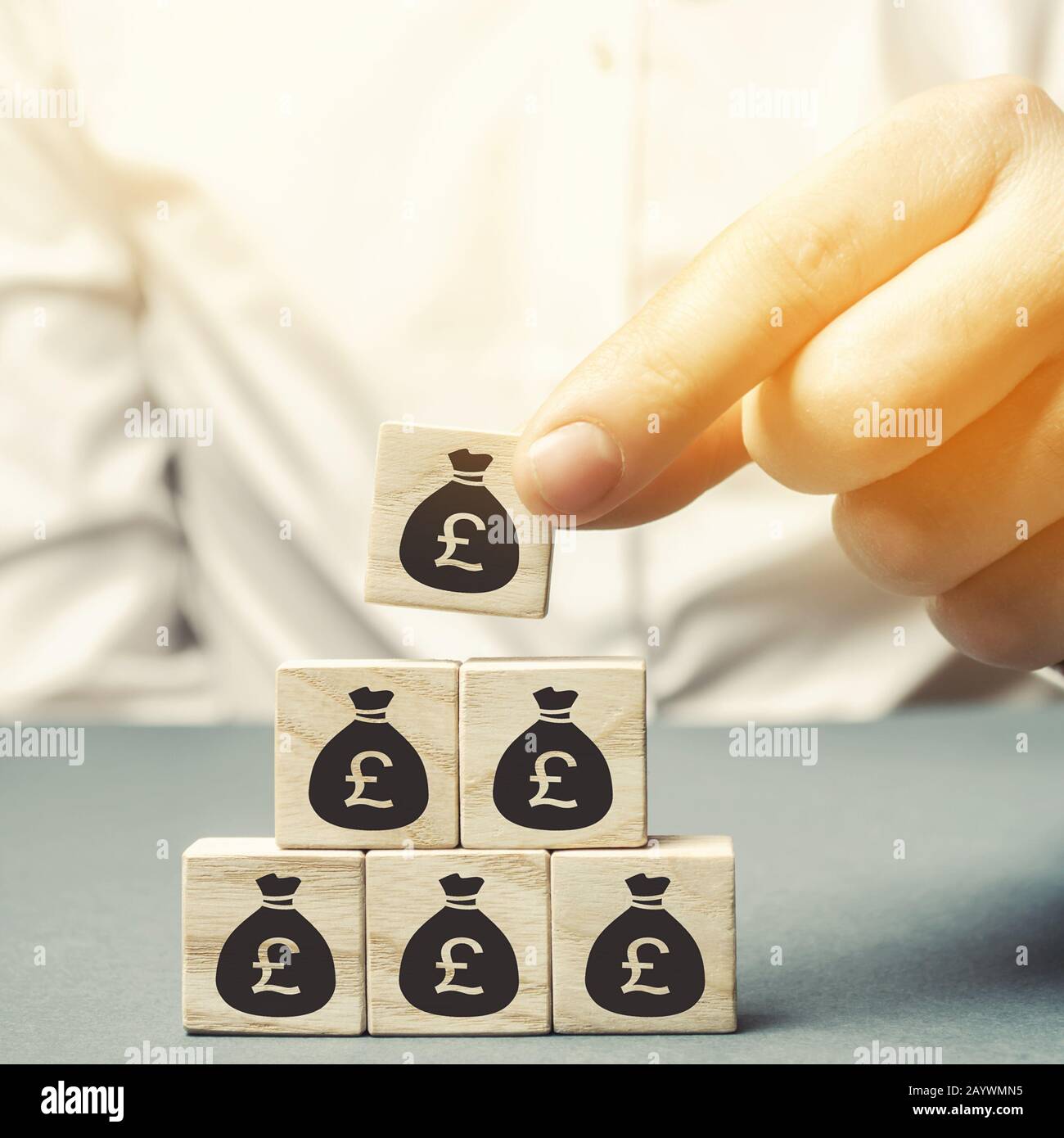 Businessman pone bloques de madera con la imagen del dinero. Concepto de negocio. Gestión de beneficios, finanzas y presupuesto. Planificación. Distribución de fondos. Capi Foto de stock
