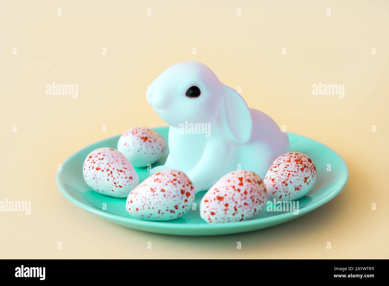 Conejo de neón de juguete blanco con un caramelo de huevos. Diseño festivo de pascua. Foto de stock