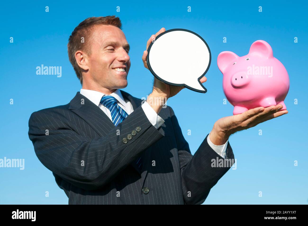 Alegre asesor financiero que mantiene una burbuja de discurso en blanco para un banco de color rosa piggy Foto de stock