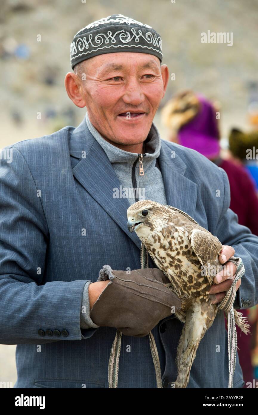 Un hombre que celebra un halcón sacador (Falco cherrug) en el Golden Eagle Festival en el recinto del festival cerca de la ciudad de Ulgii (Ölgii) en El Bayan-Ulgii Pr Foto de stock