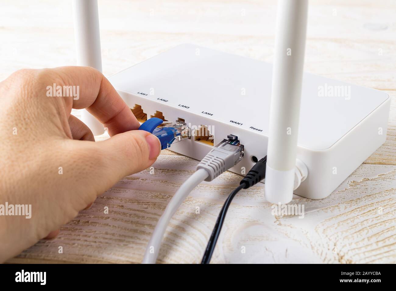 Mujer conectar un cable de red azul a la toma de un router inalámbrico  Wi-Fi blanco en una mesa blanca. Router WLAN con cables de Internet  conectados Fotografía de stock - Alamy