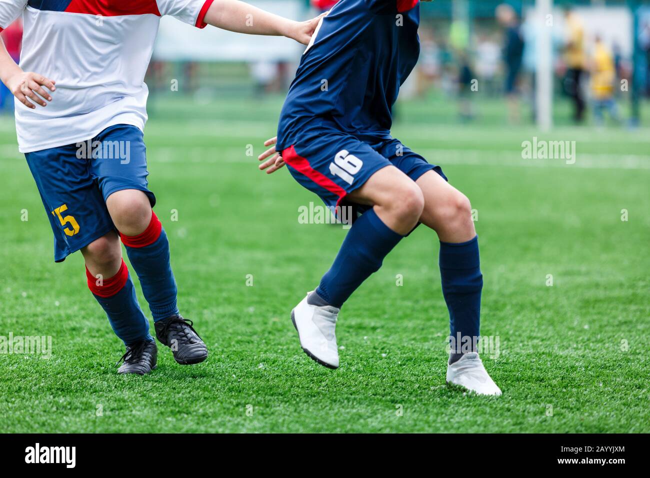 Los chicos de ropa deportiva blanca y azul juegan al fútbol en el campo,  pelota de dribles. Jóvenes jugadores de fútbol con pelota sobre hierba  verde. Entrenamiento, fútbol l Fotografía de stock -