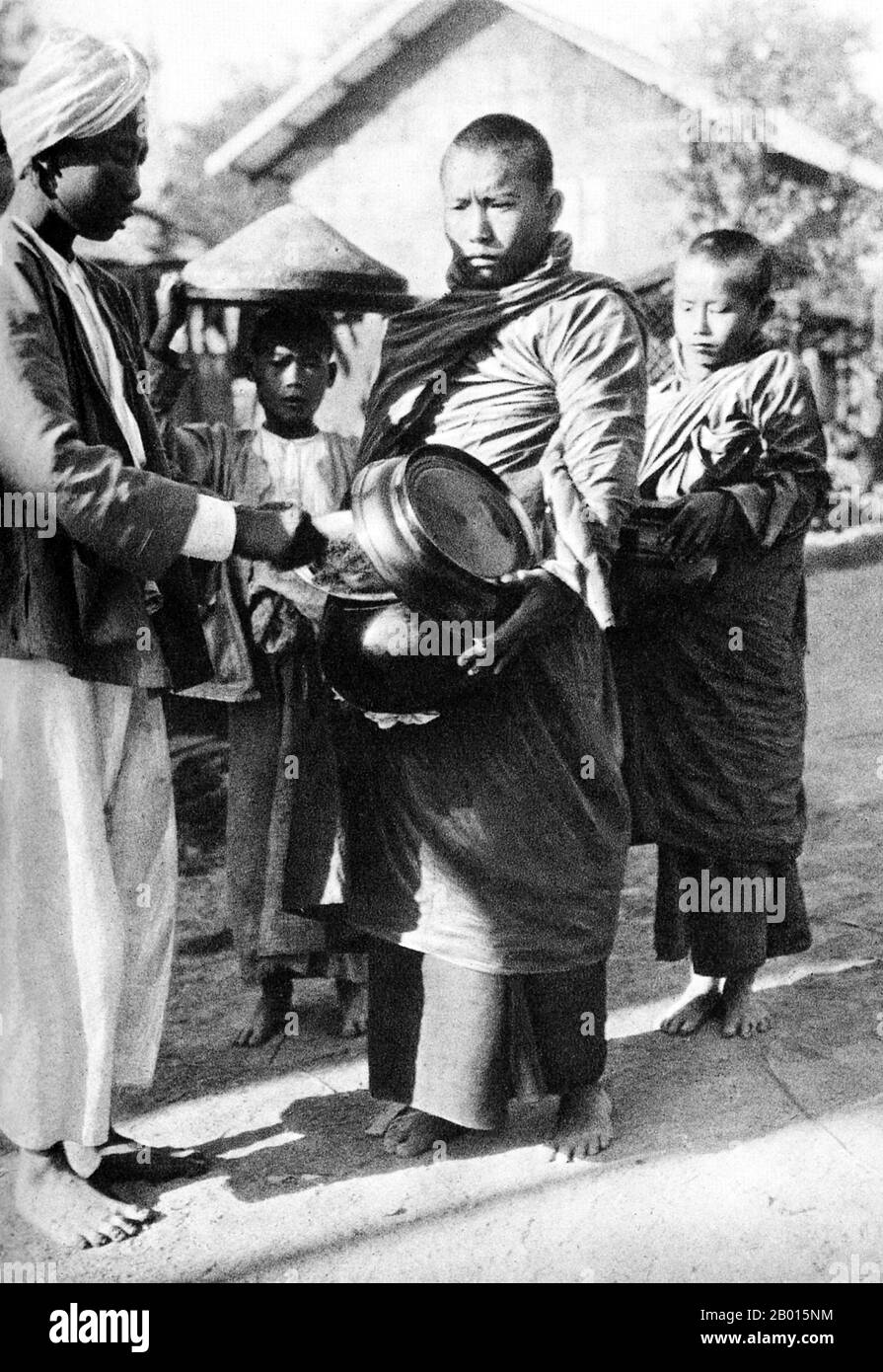 Birmania/Myanmar: Los monjes budistas recogen limosna temprano en la mañana, c. 1920s. Los monjes budistas recolectan limosna—comida preparada por devotos y laicos que hacen mérito al donar—cada mañana en Birmania y en la mayoría de los países budistas Theravada. Esta es su única comida para el día. Los monjes no comen después de las 12 del mediodía. La leyenda atribuye la primera doctrina budista en Birmania al año 228 AEC cuando Sohn Uttar Sthavira, uno de los monjes reales del emperador Ashoka el Grande de la India, vino al país con otros monjes y textos sagrados. Sin embargo, la era del budismo comenzó verdaderamente en el siglo 11th. Foto de stock