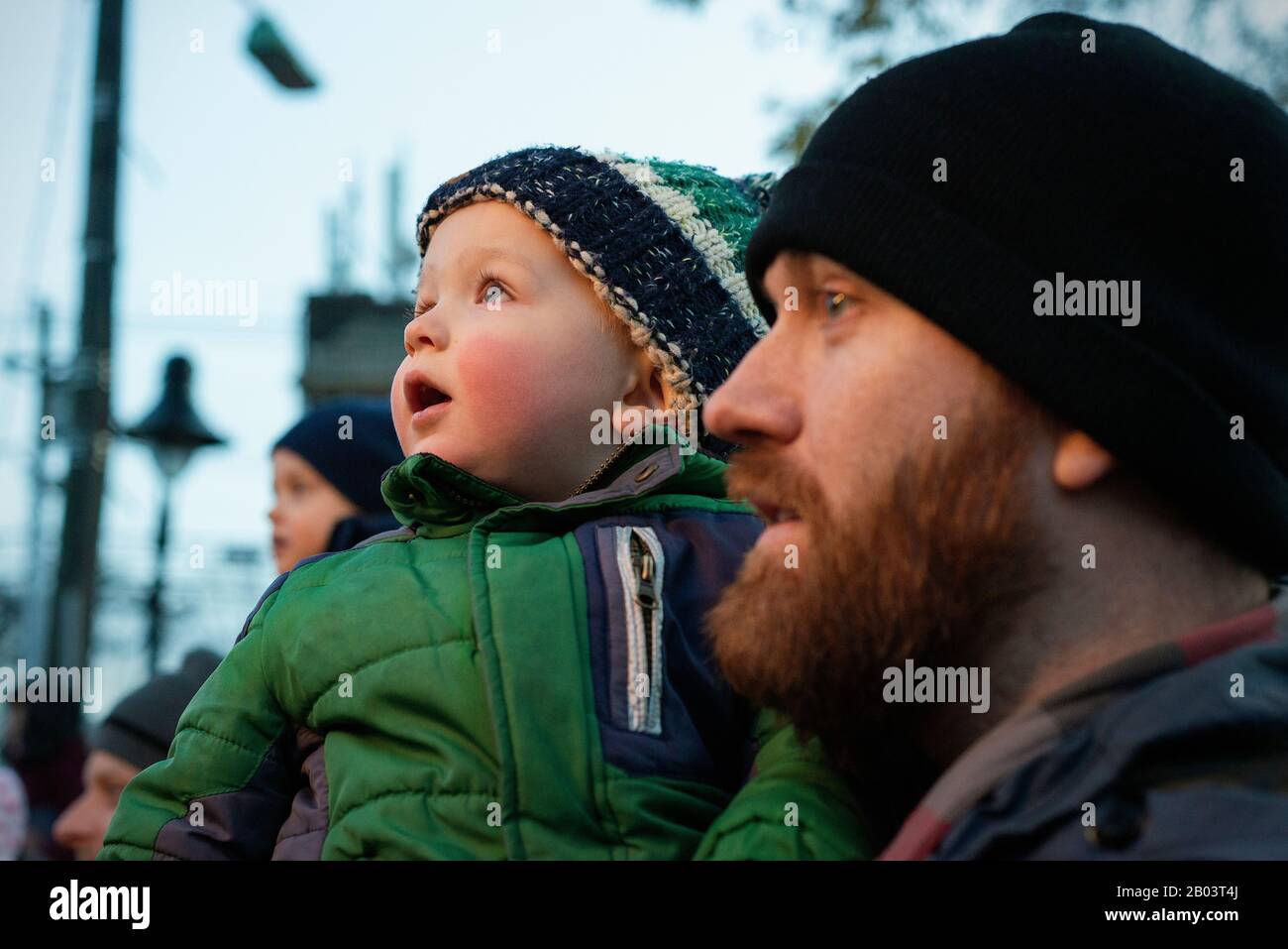 Un padre y un hijo viendo un árbol de Navidad iluminando. Foto de stock