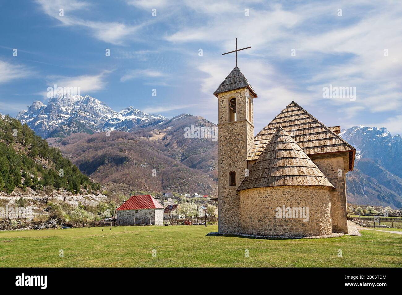 Iglesia del pueblo en el valle de Theth con montañas cubiertas de nieve en el fondo, en Albania Foto de stock