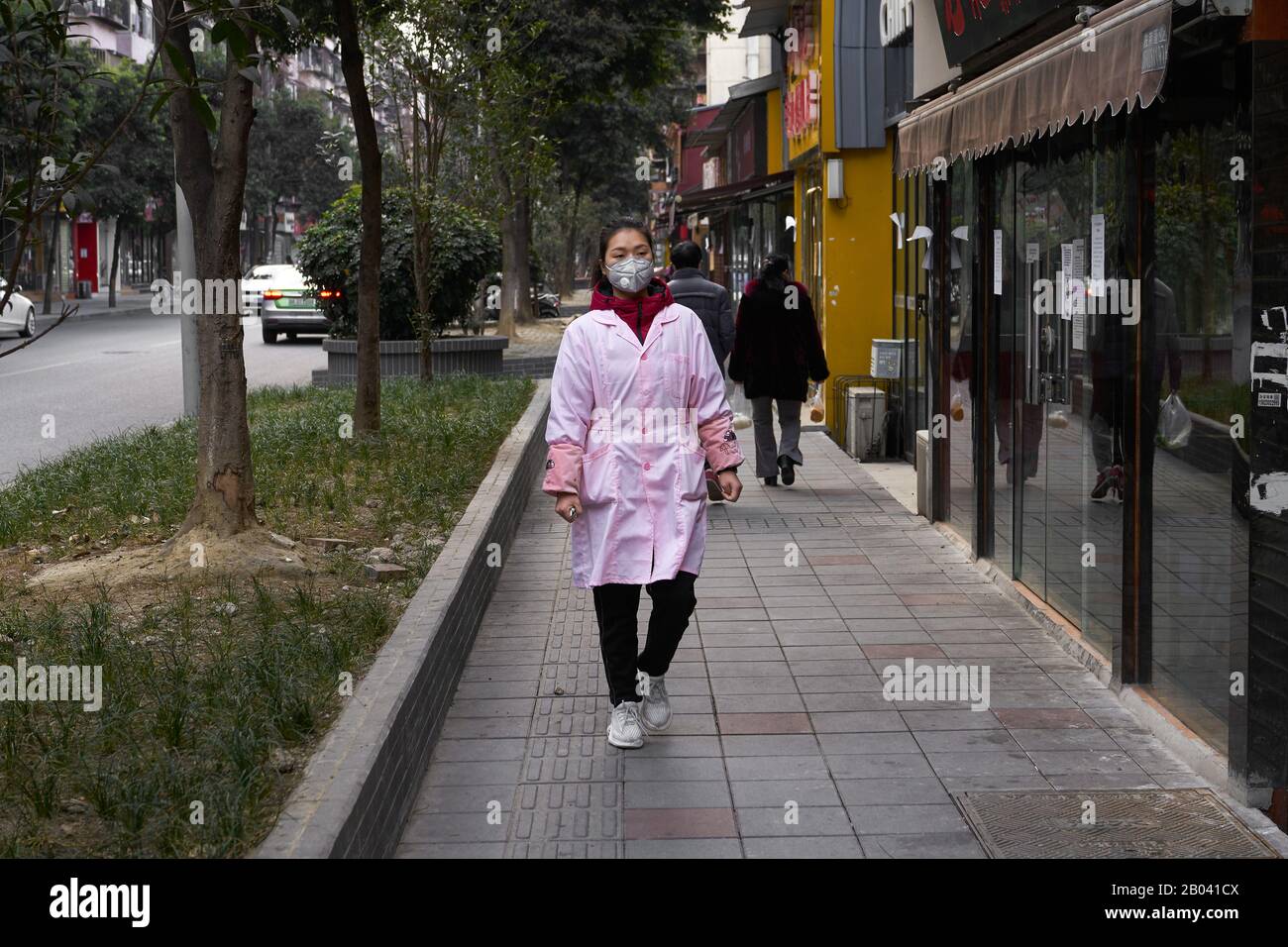 El COVID-19 en Wuhan se ha extendido por todo el mundo. Joven dama médica en la calle usando máscara quirúrgica para prevenir el coronavirus en curso. Foto de stock