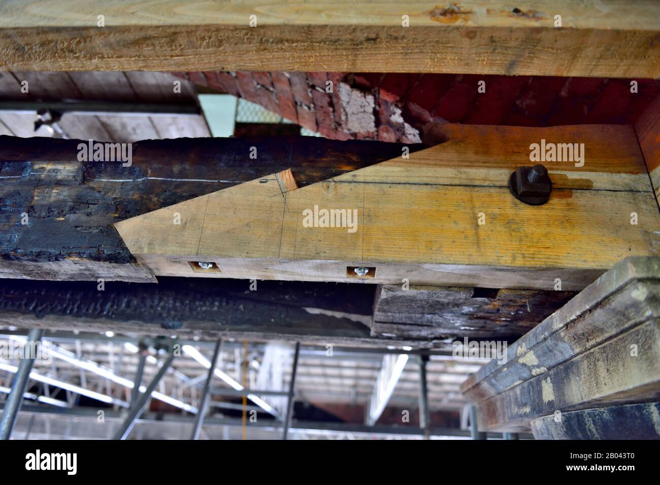 Unión de bufanda de madera atornillada y con cuña para extender una viga de techo que había sido quemada en el fuego Foto de stock