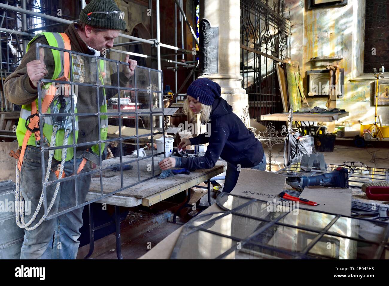 Trabajadores de vidrieras en el sitio de construcción de la restauración en el antiguo incendio dañado edificio de la iglesia siendo reutilizado, Inglaterra, Reino Unido, Foto de stock