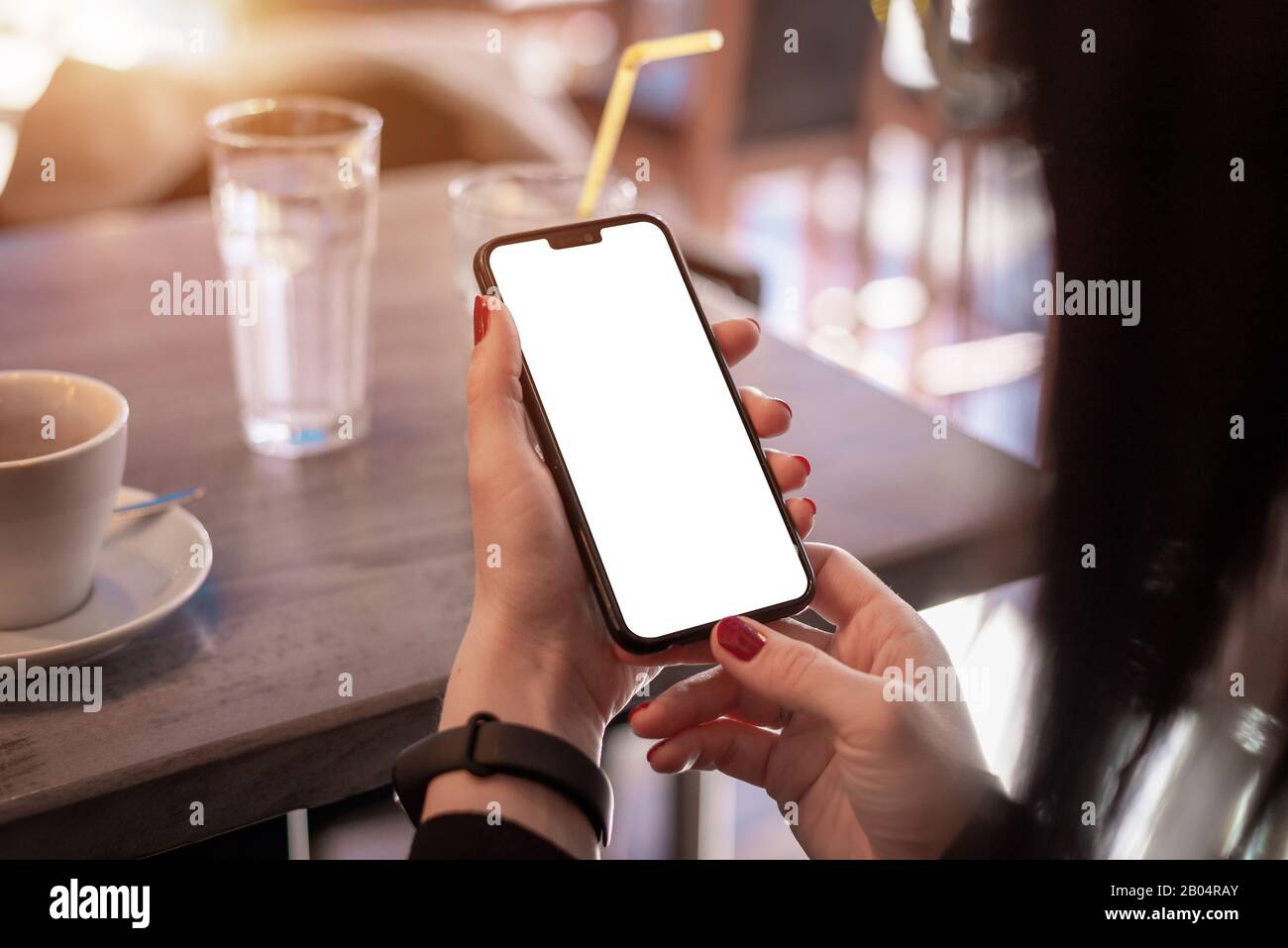 El teléfono inteligente se burla en las manos de la mujer. Concepto de uso de la aplicación para teléfono y pulsera inteligente Foto de stock