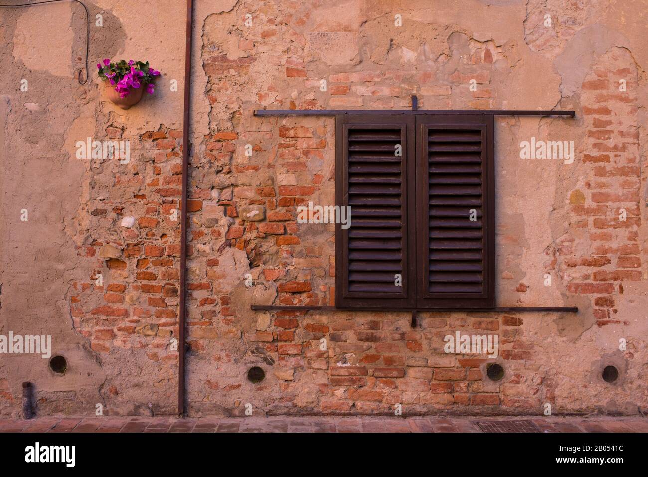 Ventana clásica de época en la antigua pared de ladrillo con persianas de madera cerradas Foto de stock