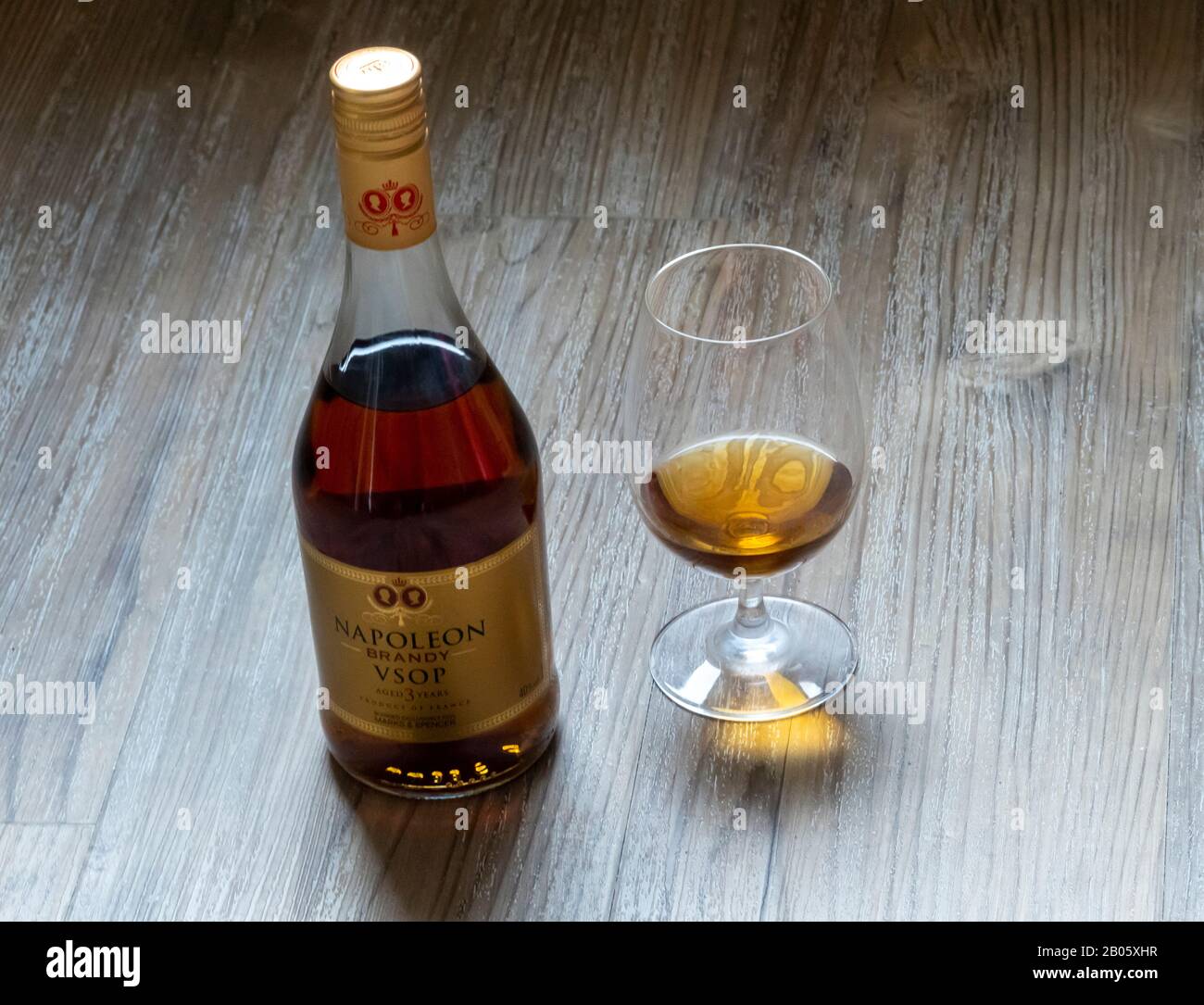 Botella y snifter de Napoleón Brandy en una mesa de madera Foto de stock