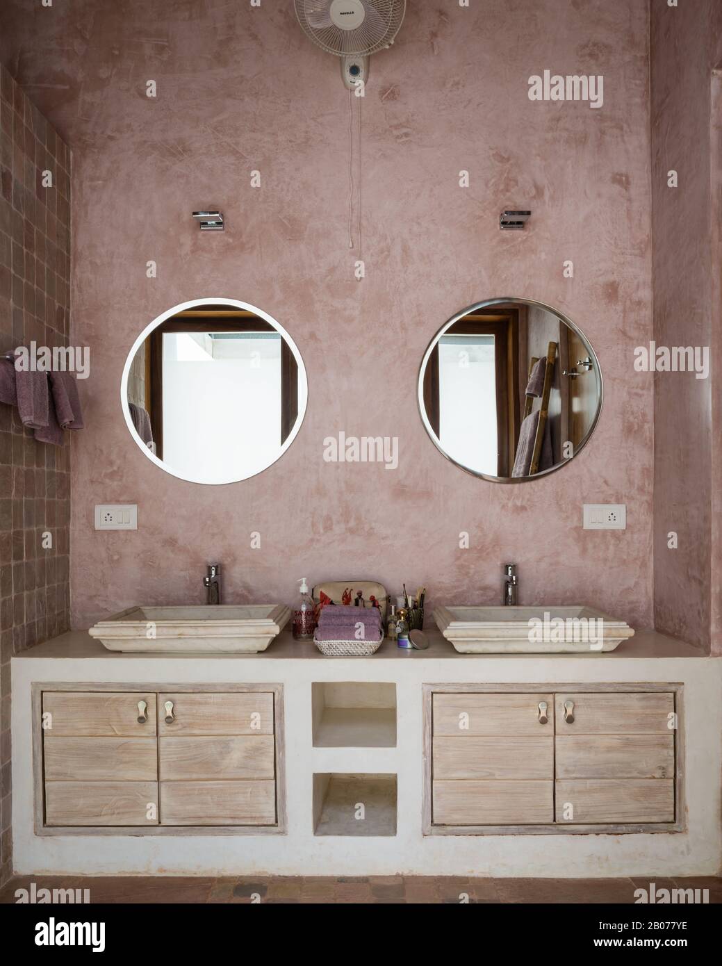 Baño en tonos rosas con espejos circulares Foto de stock