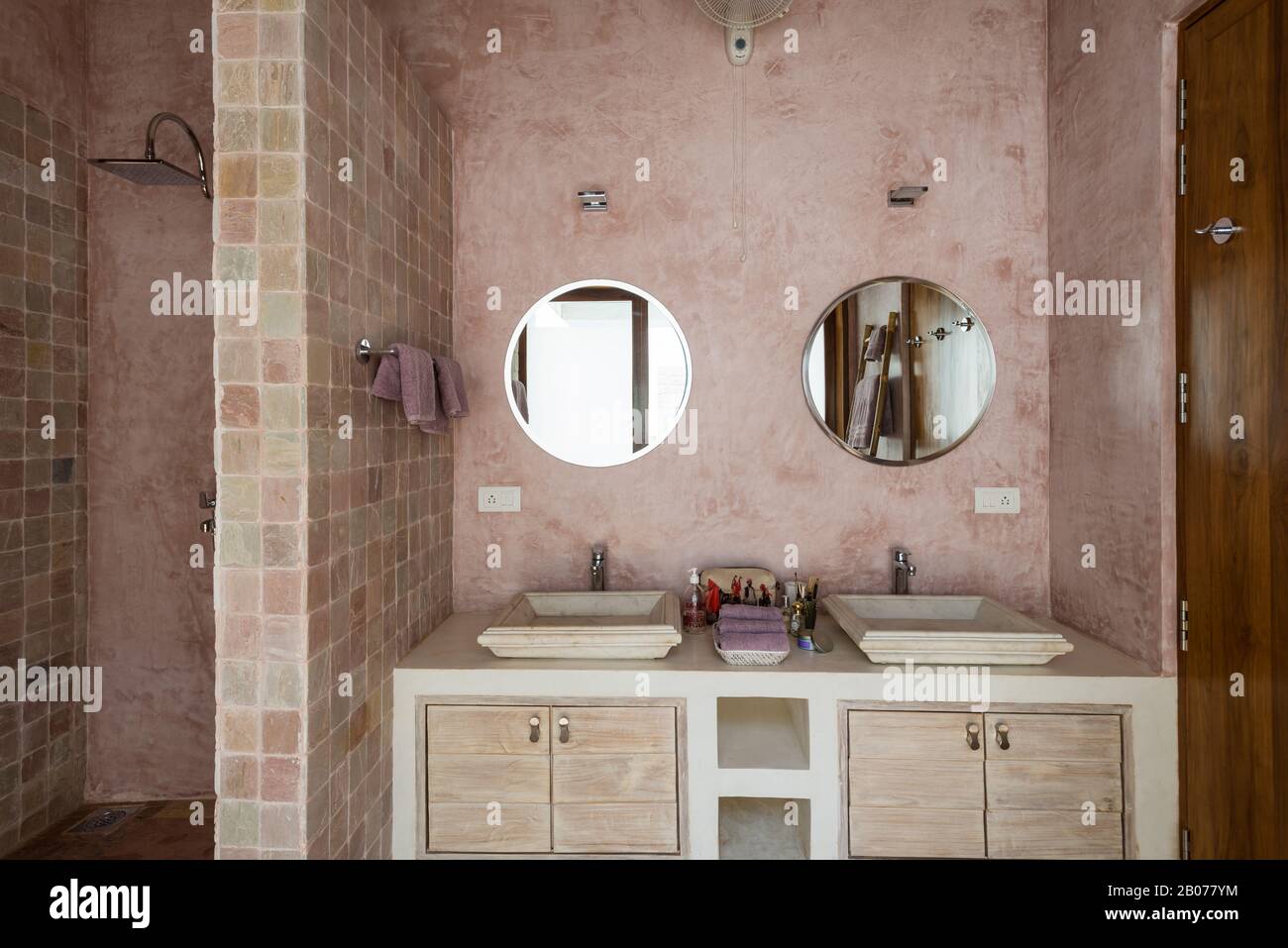 Baño en tonos rosas con espejos circulares Foto de stock