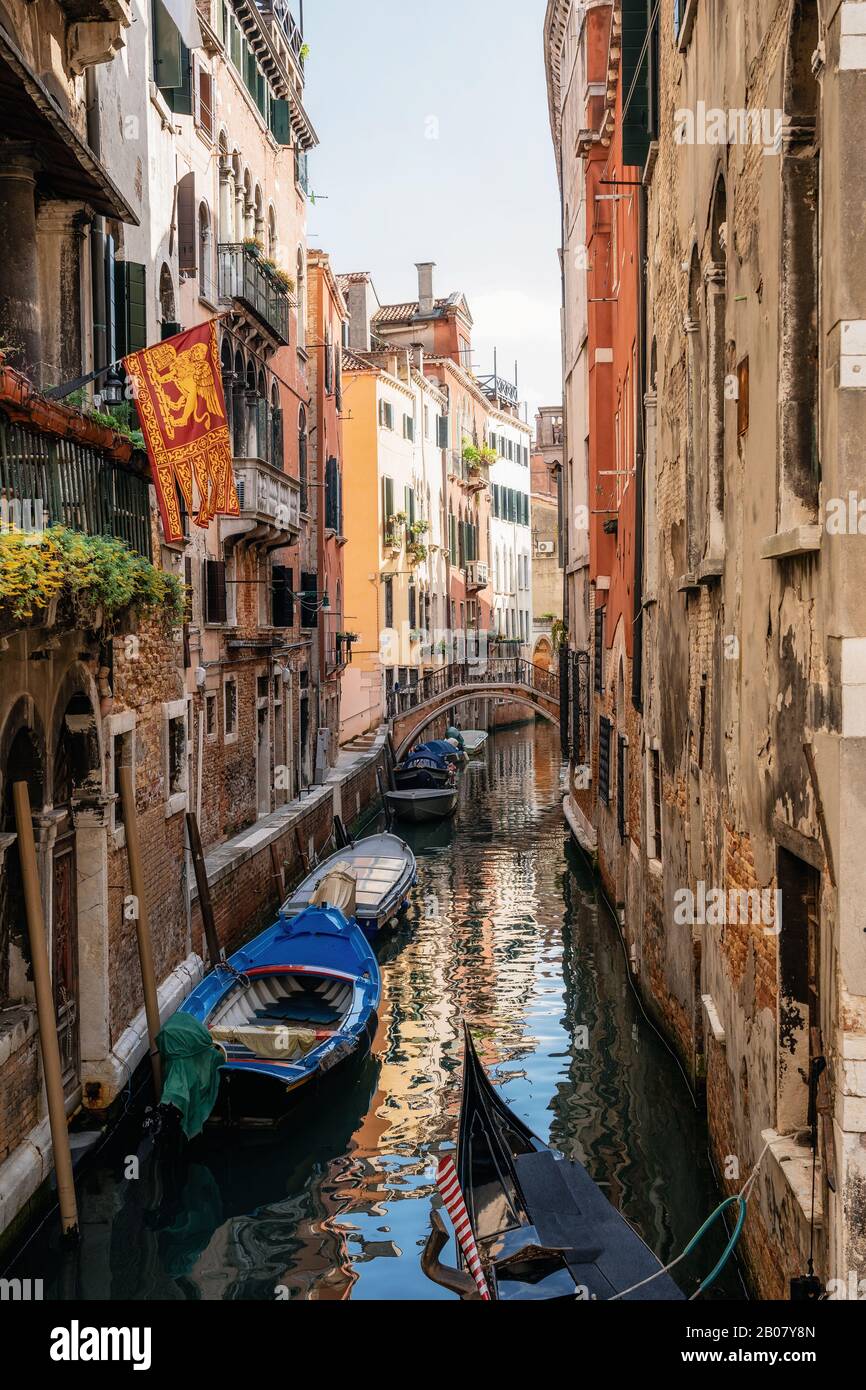 Barcos en canal estrecho entre casas antiguas, Venecia, Italia Foto de stock