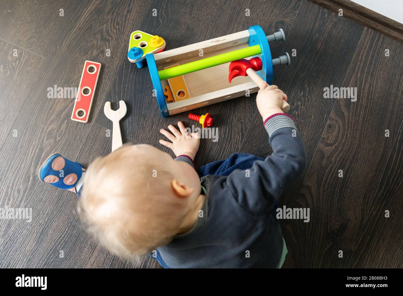 niño jugando con caja de herramientas de juguete de madera en el suelo de la casa Foto de stock