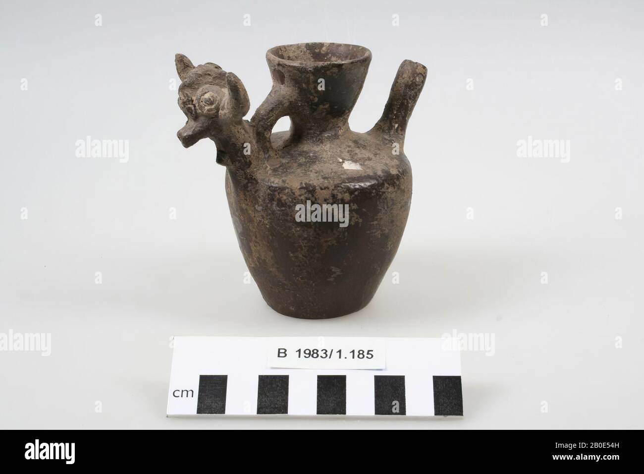 Una jarra o lata de barro con boquilla tubular y cuello y borde en forma de embudo. Una oreja vertical conecta el cuello con el hombro. En la parte inferior del mango hay un proto animal para ver con cuernos torcidos y ojos impuestos, tal vez una cabra o ibex. Quizás falso., Vajilla, alfarería, H 10.7 cm, D 7.5 cm, W 11.2 cm, D borde 4.1 cm, Edad de Hierro II 1000-800 BC, Irán Foto de stock