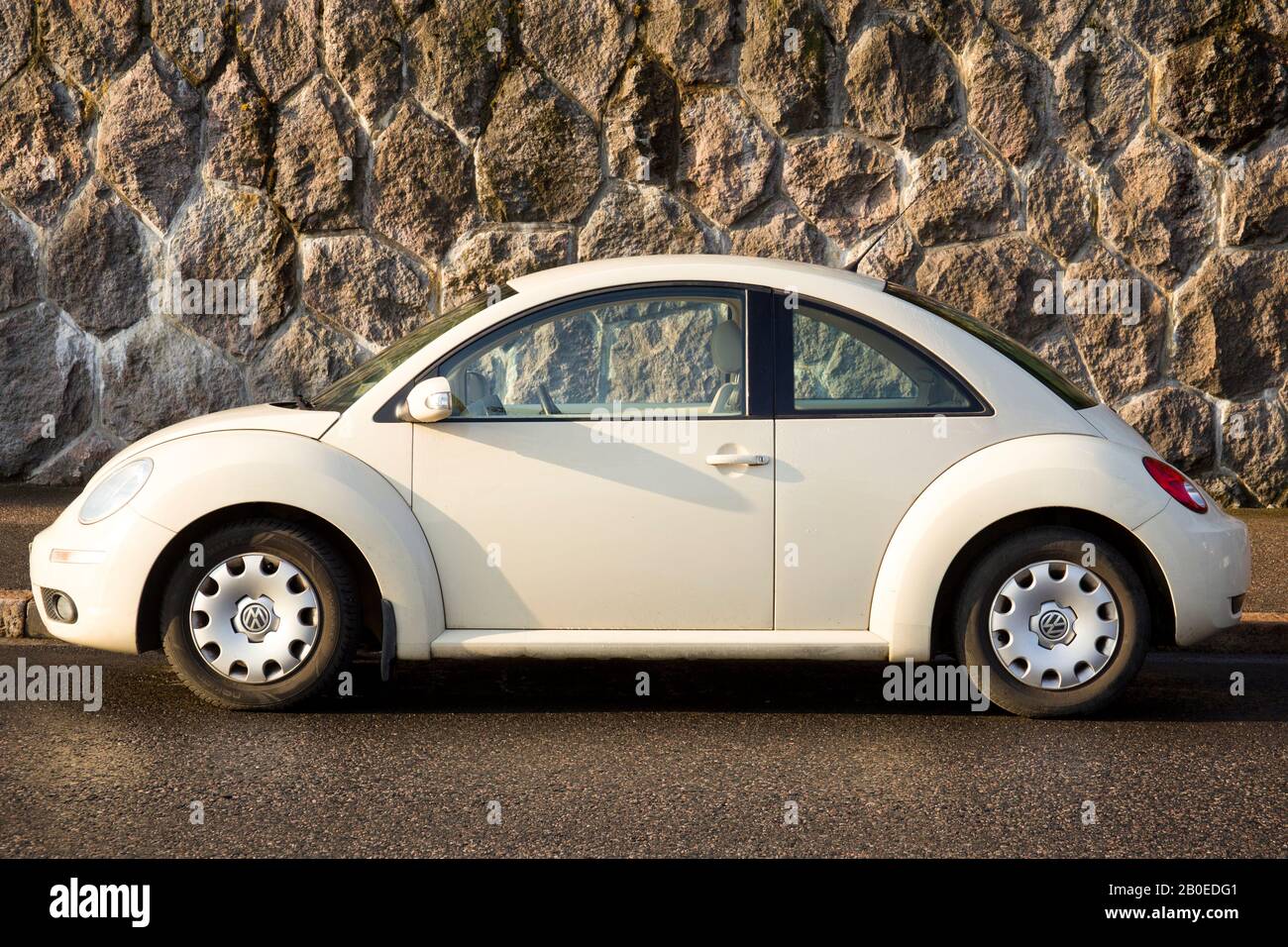 Coche blanco vintage Volkswagen en una pared de piedra al sol de la mañana Foto de stock