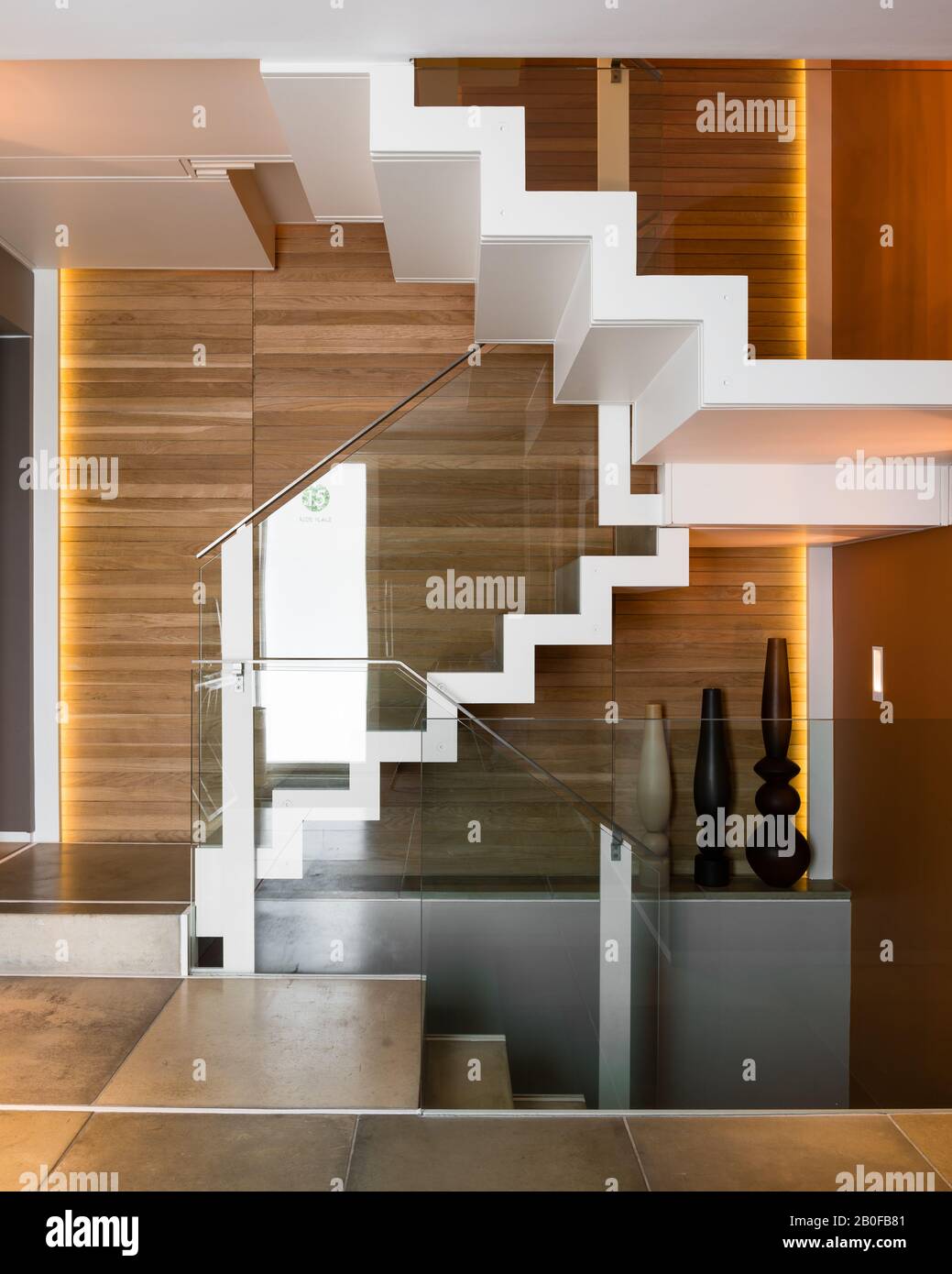 Escalera con paneles de madera y barandilla moderna de cristal en los apartamentos del oeste de Londres Foto de stock