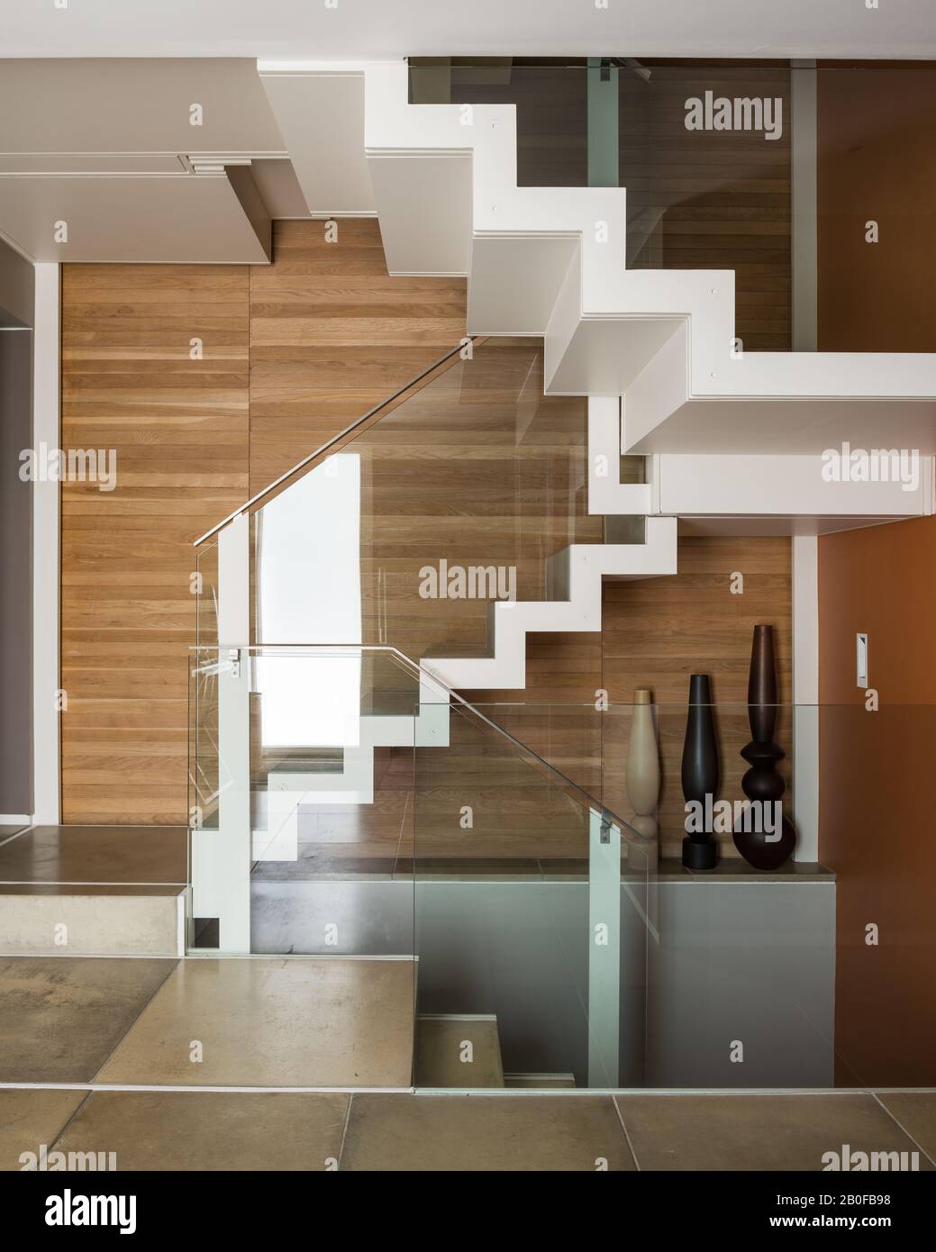 Escalera con paneles de madera y barandilla moderna de cristal en los apartamentos del oeste de Londres Foto de stock