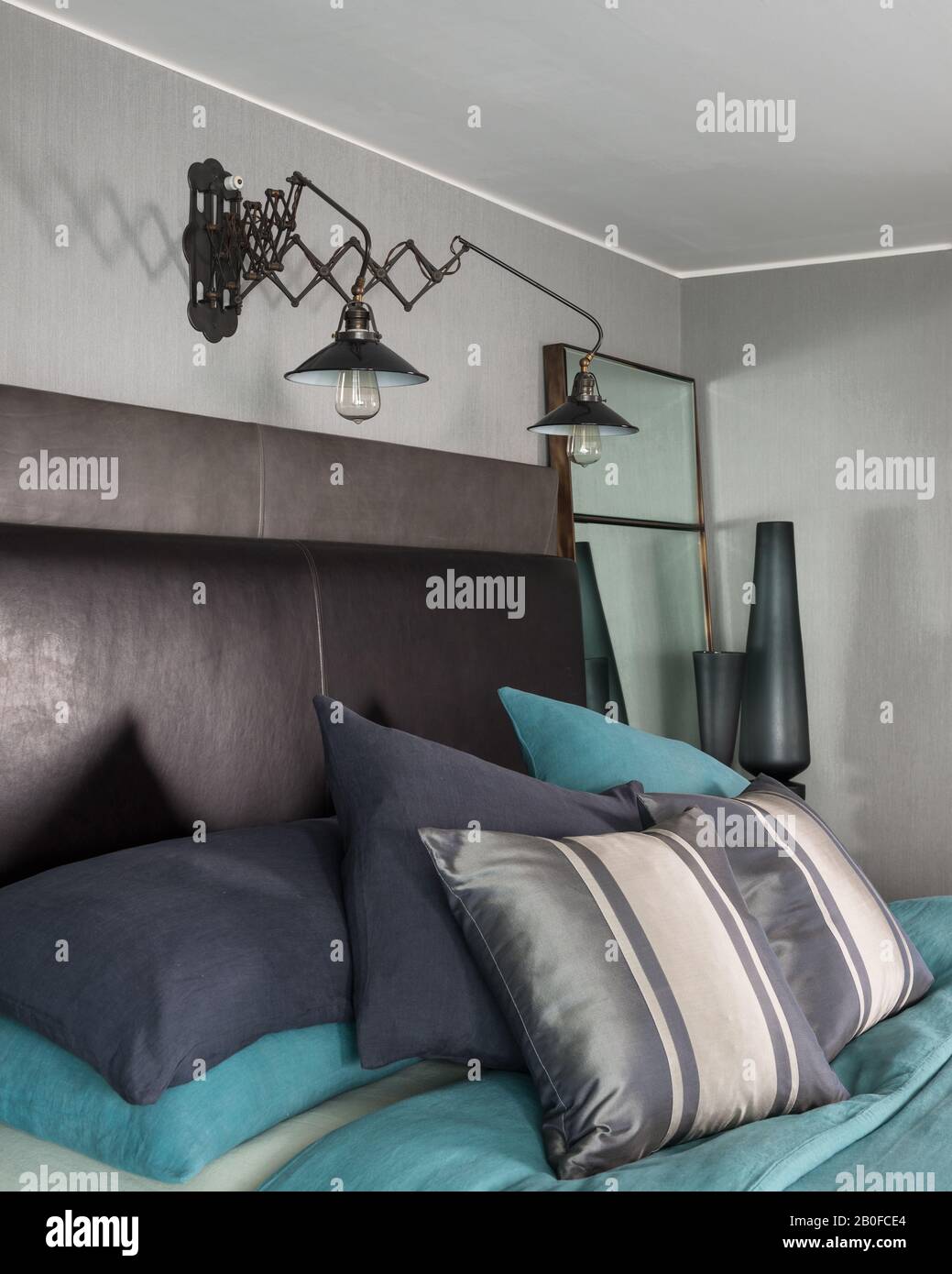 Anglepoise lam iluminado sobre la cama con cabecera de cuero marrón en el moderno apartamento del oeste de Londres. Foto de stock