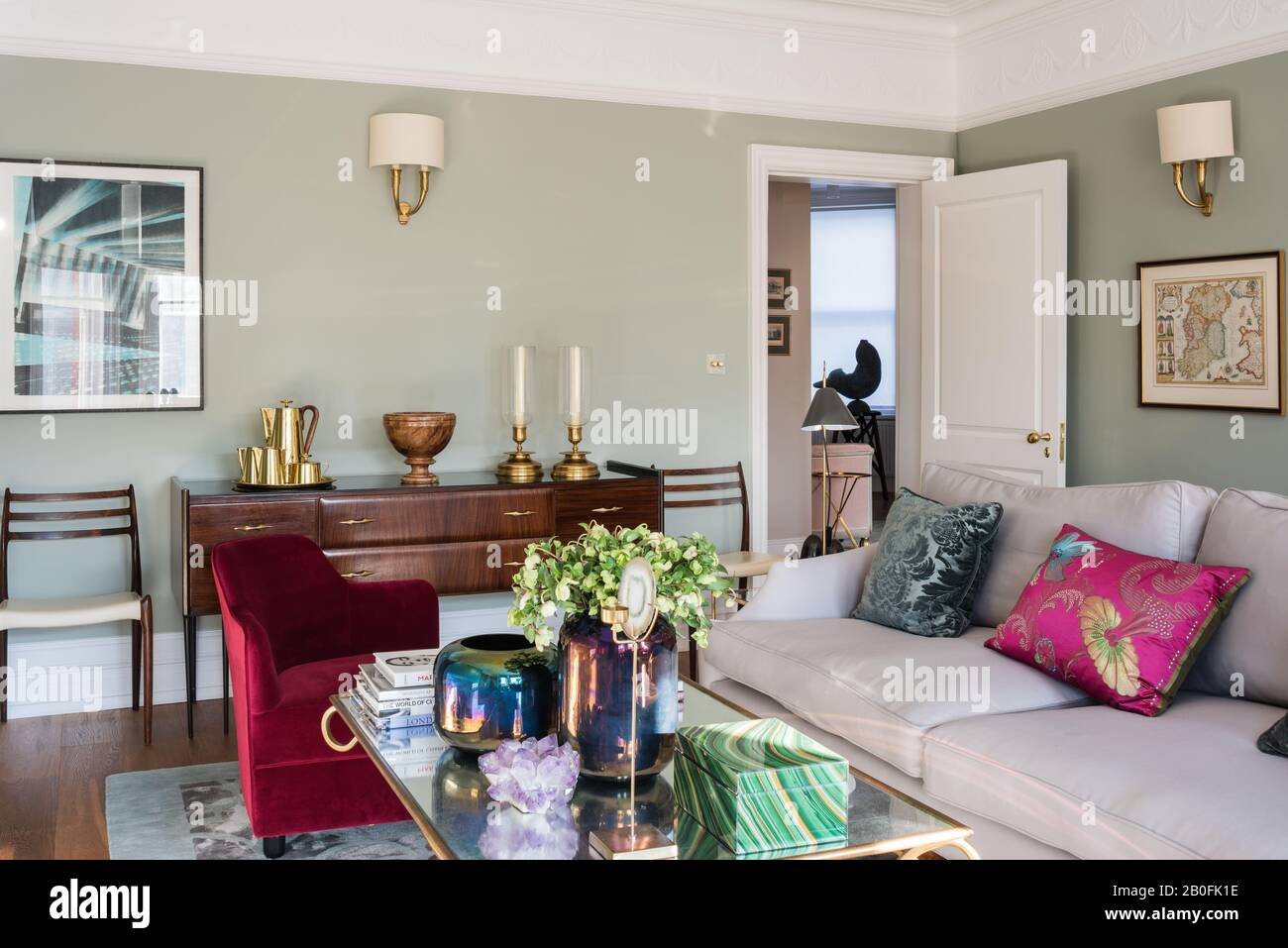 Mezcla de piezas antiguas y contemporáneas en el rediseño victoriano con un sillón a la última en terciopelo rojo Foto de stock