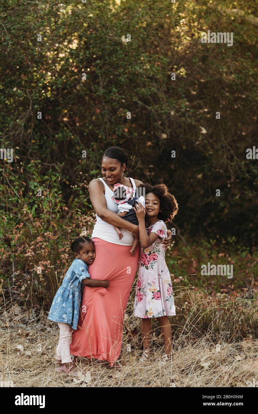 Retrato de una madre joven y tres niñas de pie en el campo Foto de stock