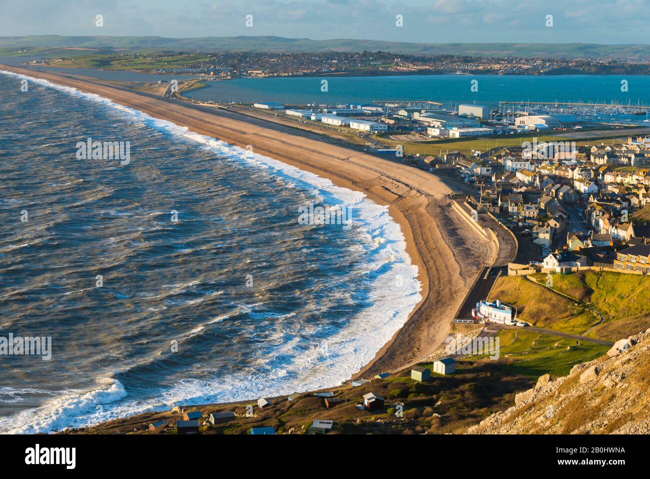 Fortuneswell, Portland, Dorset, Reino Unido. 20 de febrero de 2020. El tiempo en Reino Unido. Vista desde la cima de los acantilados de West Weares a través de Fortuneswell en la isla de Portland en Dorset durante el sol de última hora de la tarde con vientos y mares agitados rompiendo en tierra en Chesil Beach en Chiswell. Crédito De La Imagen: Graham Hunt/Alamy Live News Foto de stock