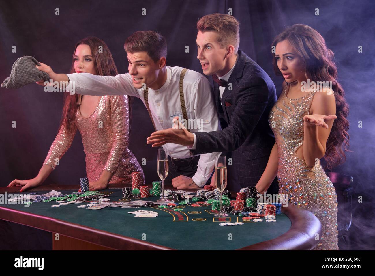 Amigos jugando al póker en el casino, en la mesa con montones de fichas,  dinero, cartas, champán. Me quedé decepcionado. Fondo negro. Primer plano  Fotografía de stock - Alamy