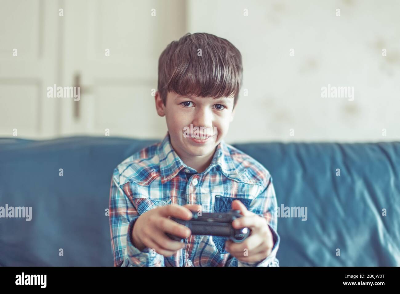 Niño jugando video juego por control en casa Foto de stock