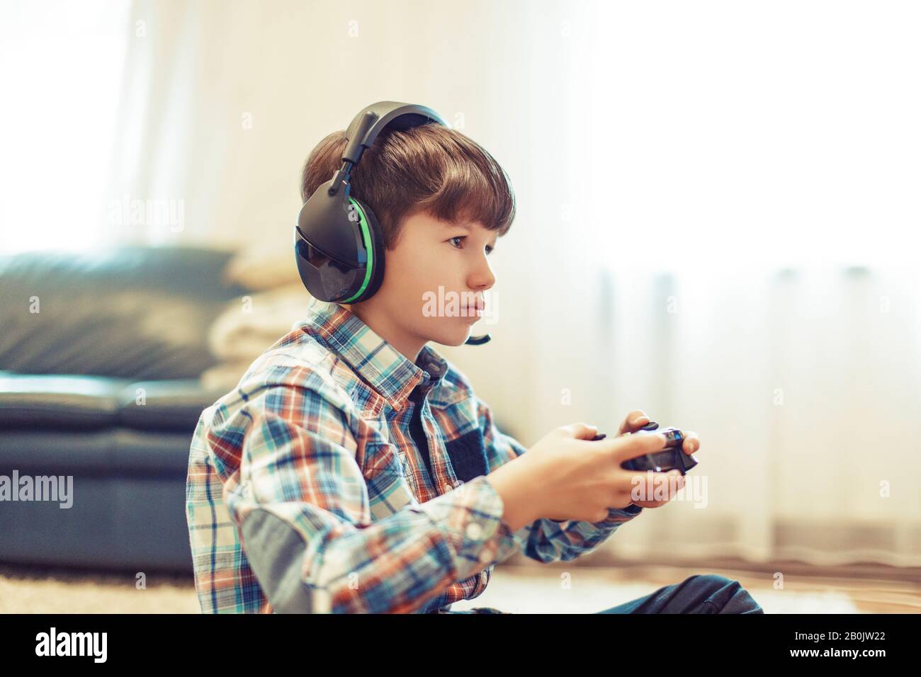 Joven jugador niño concentrarse mientras juega, sosteniendo controlador Foto de stock