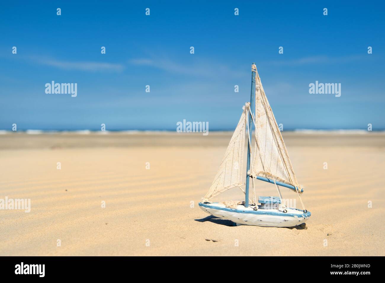 Barco de vela de juguete en miniatura en la playa Foto de stock