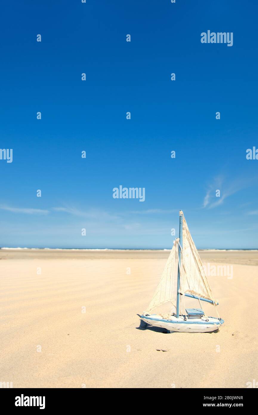 Barco de vela de juguete en miniatura en la playa Foto de stock