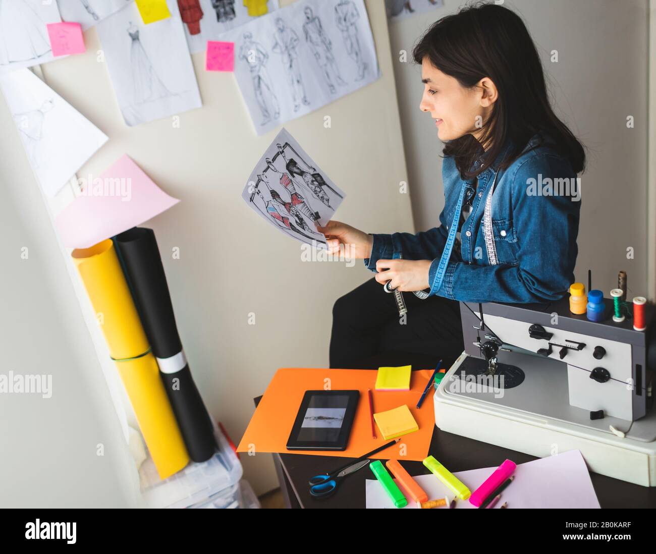 Retrato de una joven diseñadora de moda femenina en su taller. Chica joven y exitosa Foto de stock