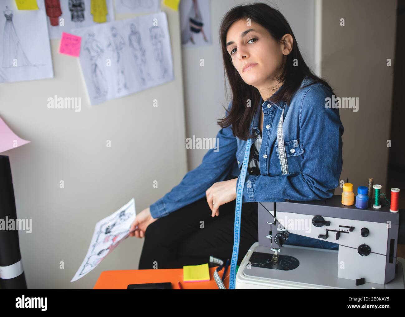Retrato de una joven diseñadora de moda femenina en su taller. Chica joven y exitosa Foto de stock