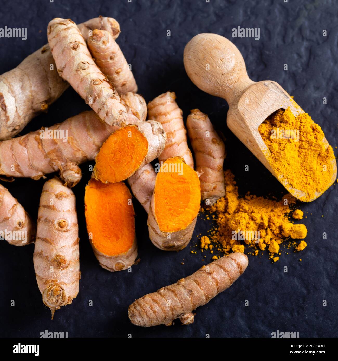 Comida y bebida, nutrición dietética, concepto de atención médica. Raíz cúrcuma de naranja natural cruda y polvo, cucuma longa sobre una mesa de cocción de lechugas. Orie indio Foto de stock