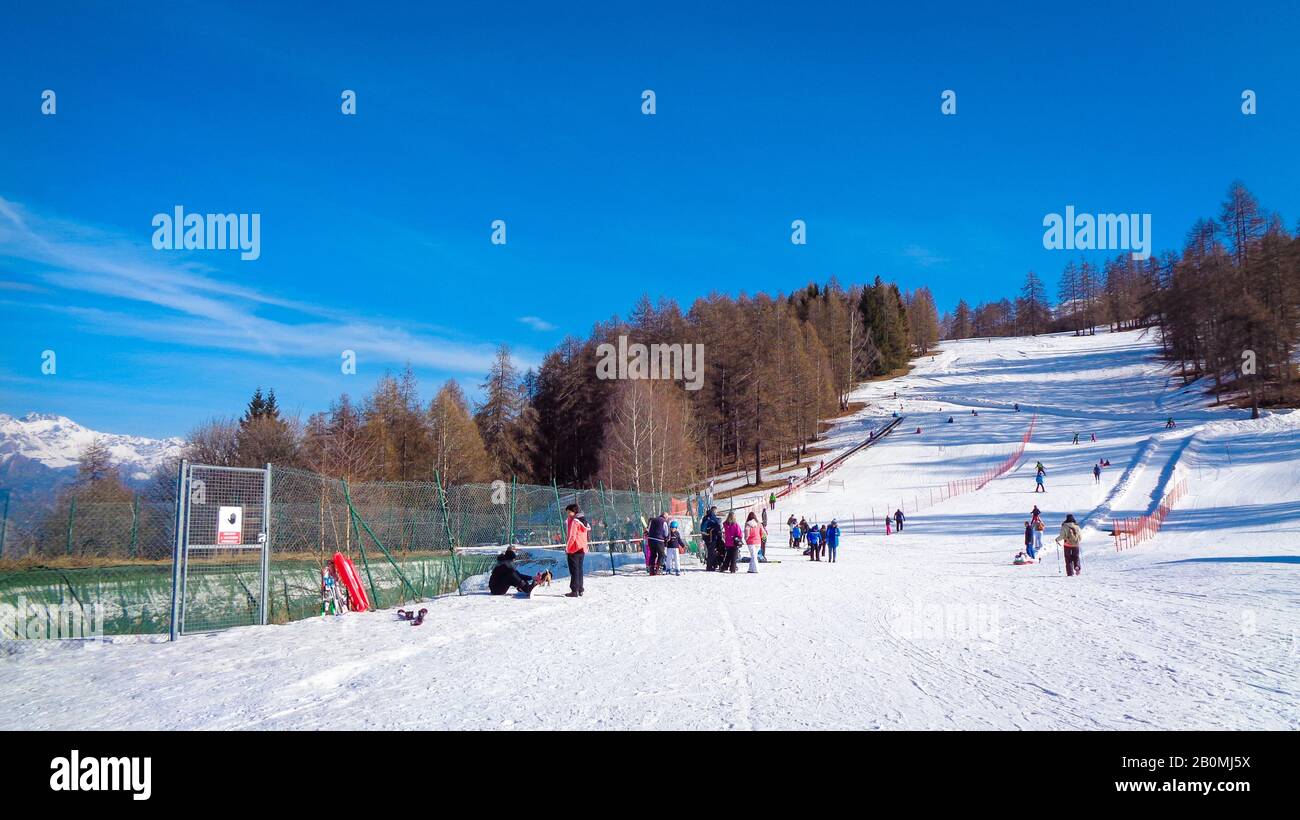 Paisaje de montaña con nieve de invierno y la gente disfruta del esquí bajo el cielo azul, Italia Foto de stock