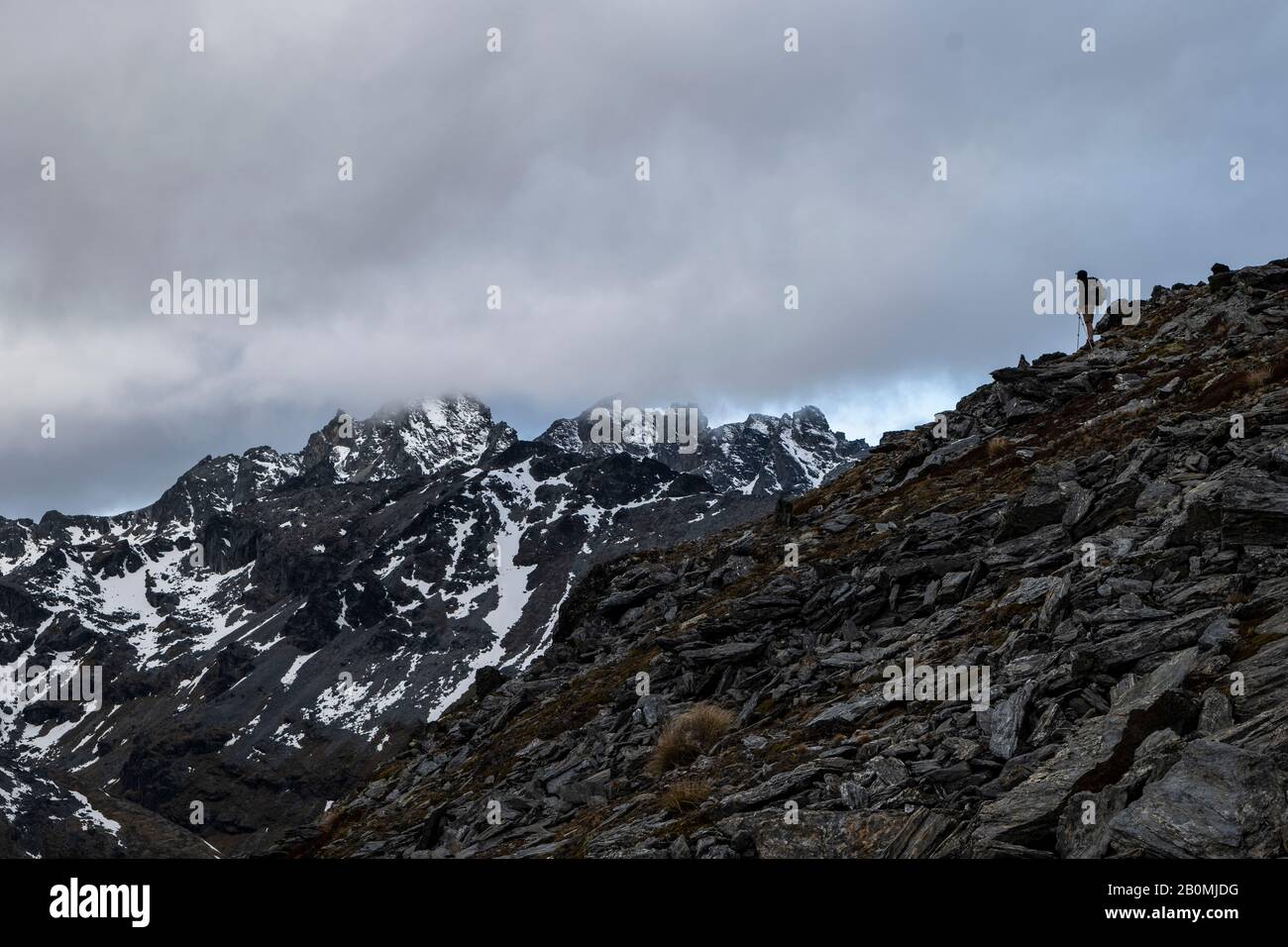 Figura en una cresta rocosa, en las montañas nevadas de Nueva Zelanda Foto de stock