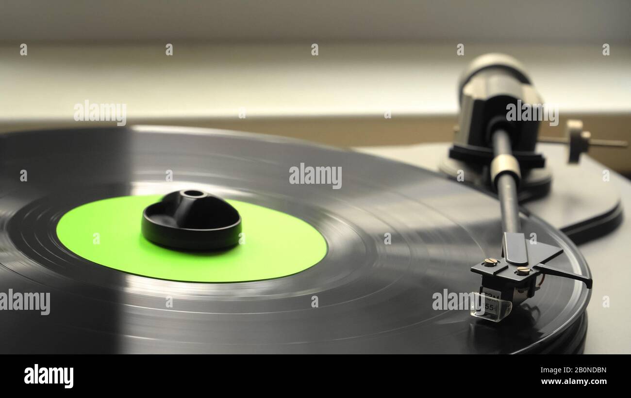 El reproductor de discos de vinilo está sobre la mesa, y un mecanismo de cabeza de aguja toca el disco negro vintage con una banda sonora. Foto de stock