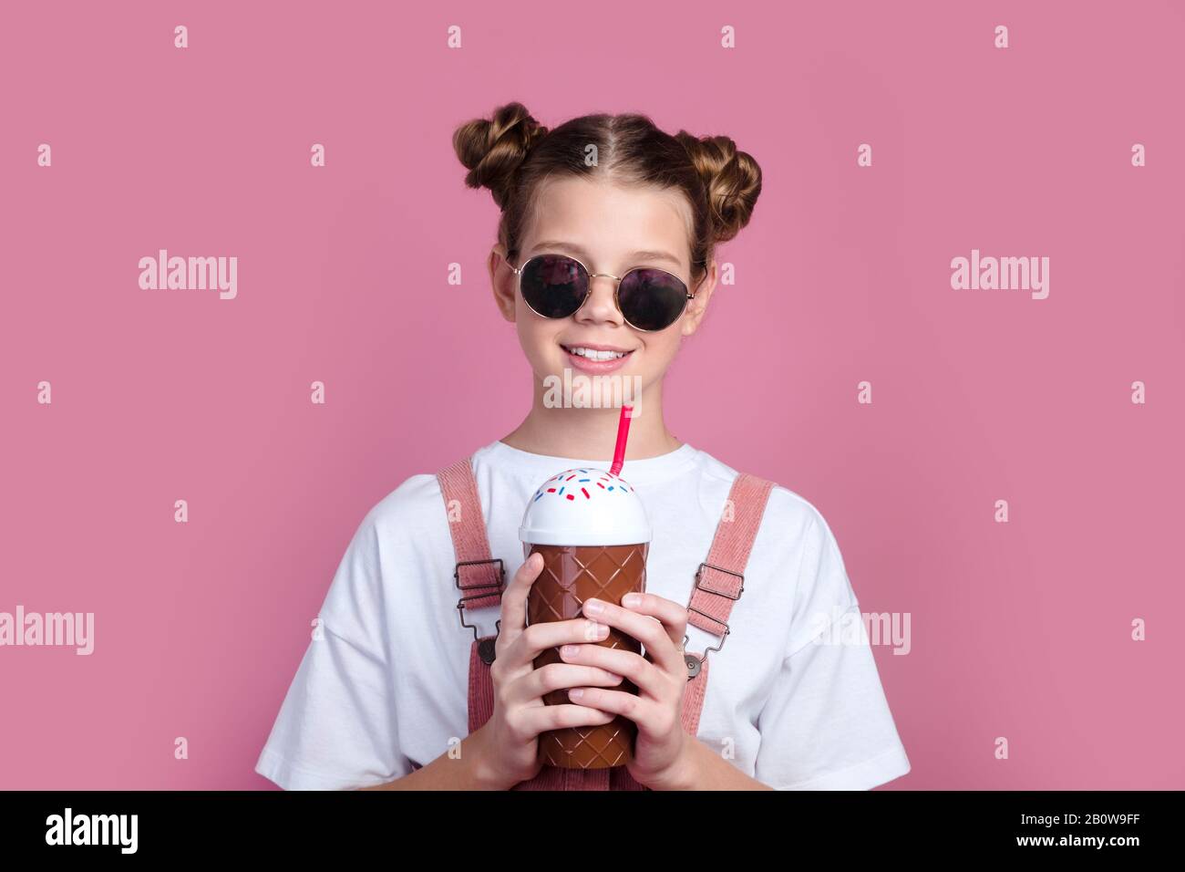 Bonita niña con ropa informal y gafas de sol en rosa con cóctel frío  Fotografía de stock - Alamy