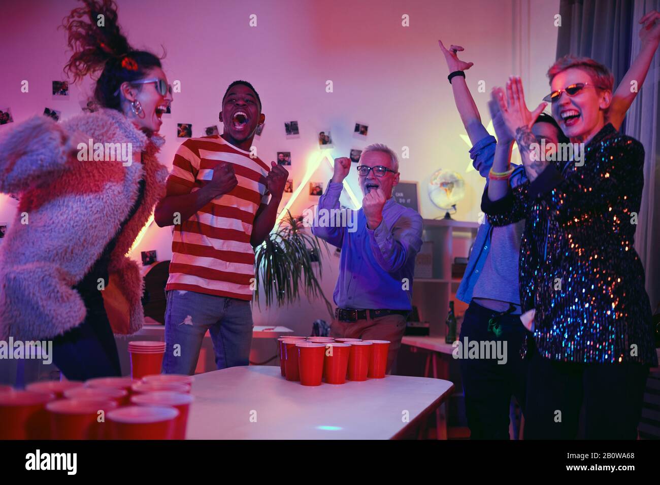 Grupo de personas felices juntos en la fiesta durante el juego de beer pong Foto de stock