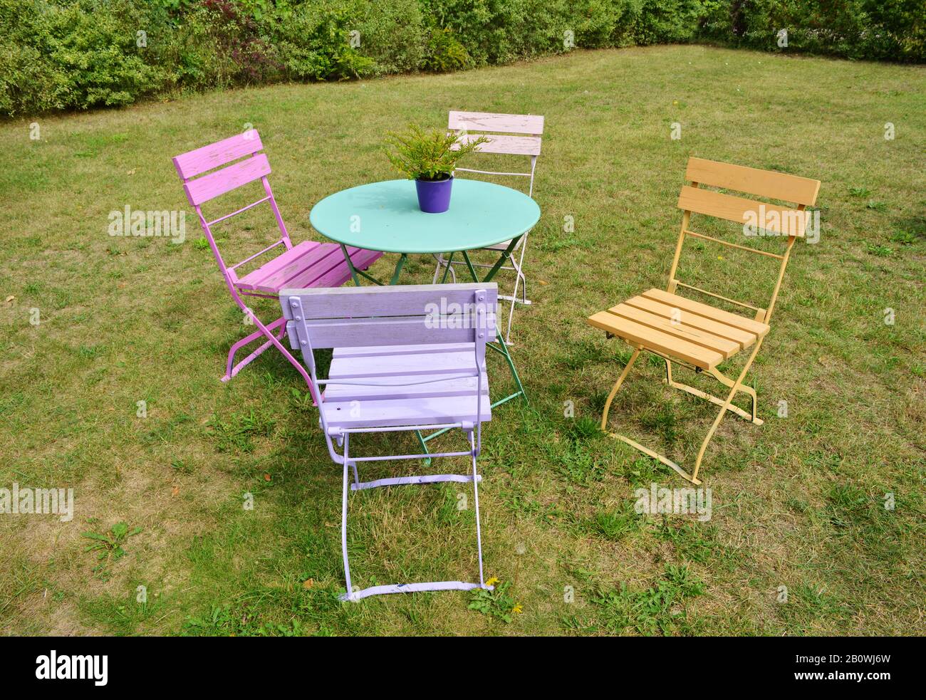 Hermosas sillas de colores vintage y mesa de jardín al aire libre en una  hierba verde Fotografía de stock - Alamy