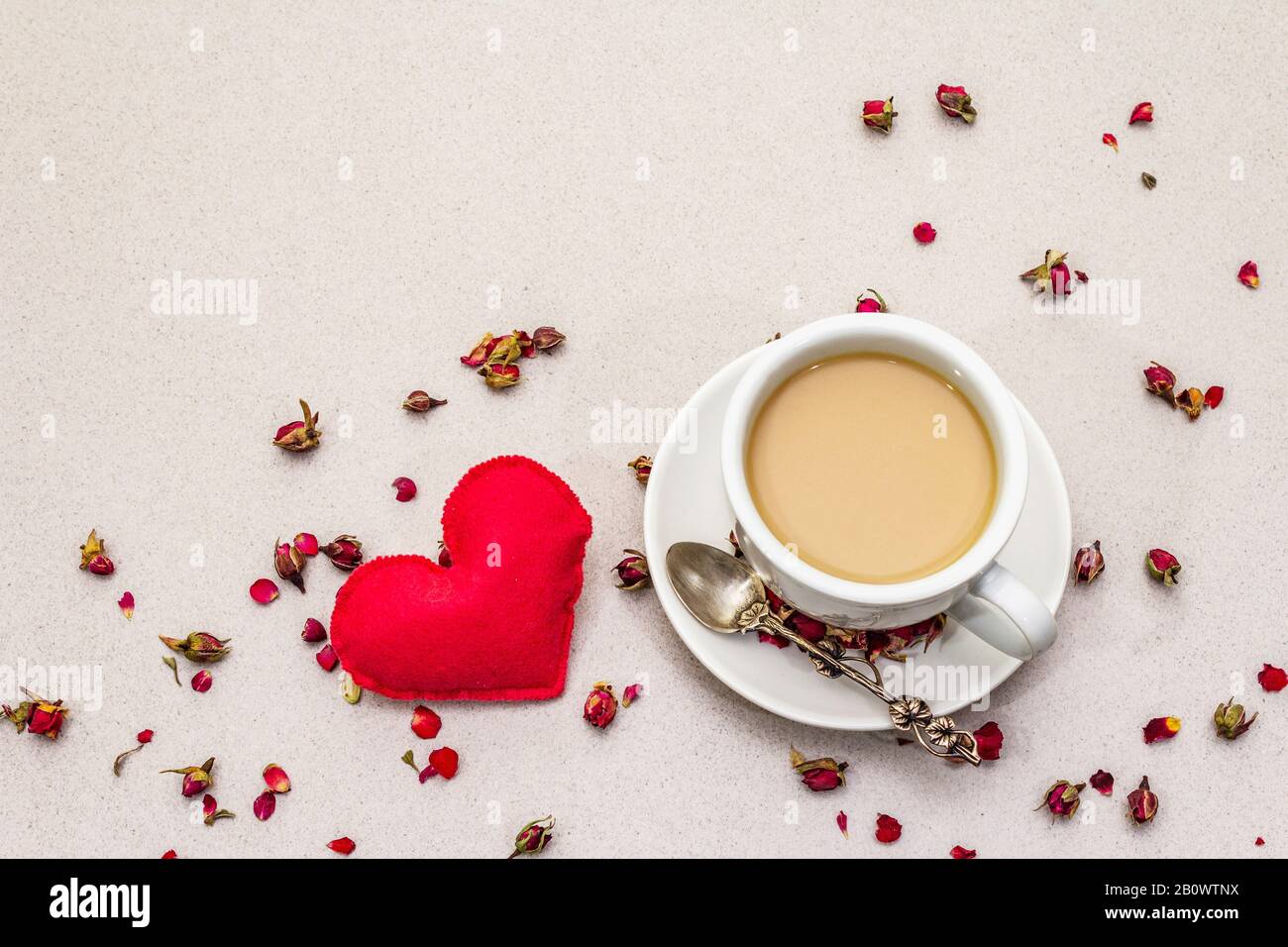 Buenos días. Taza de café, capullos de rosa y pétalos, corazón de fieltro  rojo. Desayuno romántico el día de San Valentín. Fondo de hormigón de  piedra, espacio de copia Fotografía de stock -