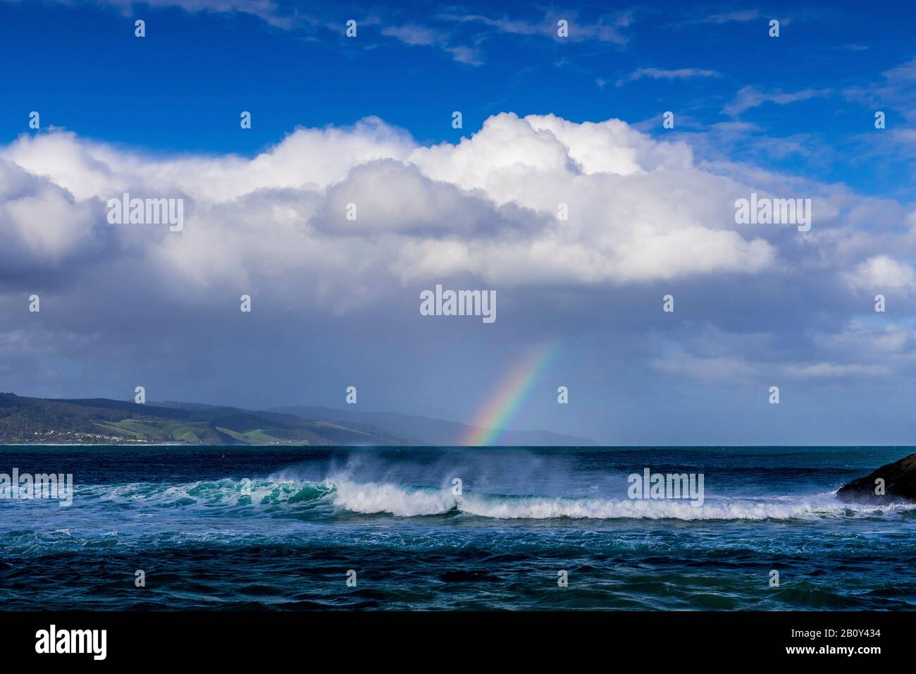 Apollo Bay con la lluvia acercándose causando un pequeño arco iris que se forma sobre el agua. Victoria, Australia Foto de stock