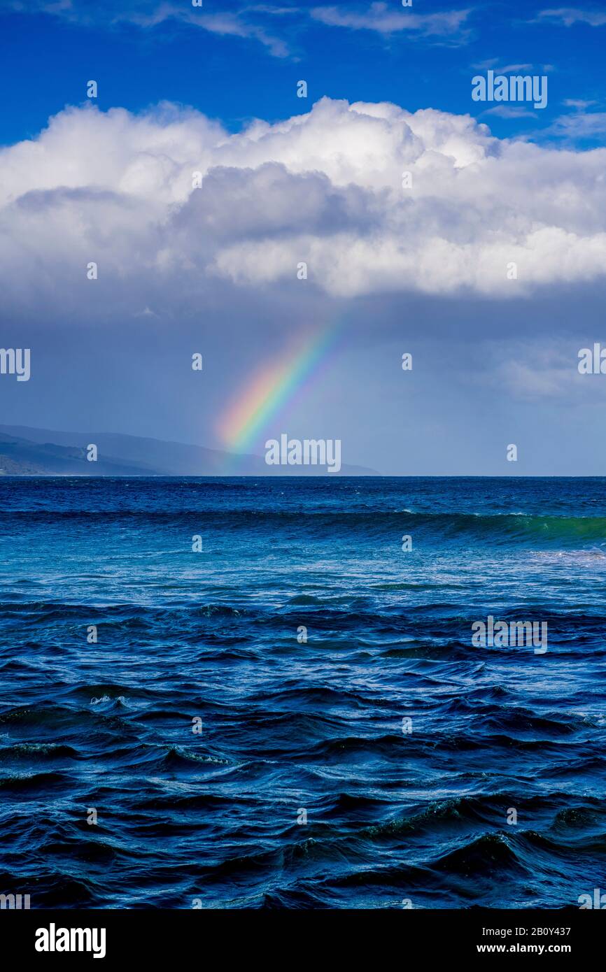 Apollo Bay con la lluvia acercándose causando un pequeño arco iris que se forma sobre el agua. Victoria, Australia Foto de stock