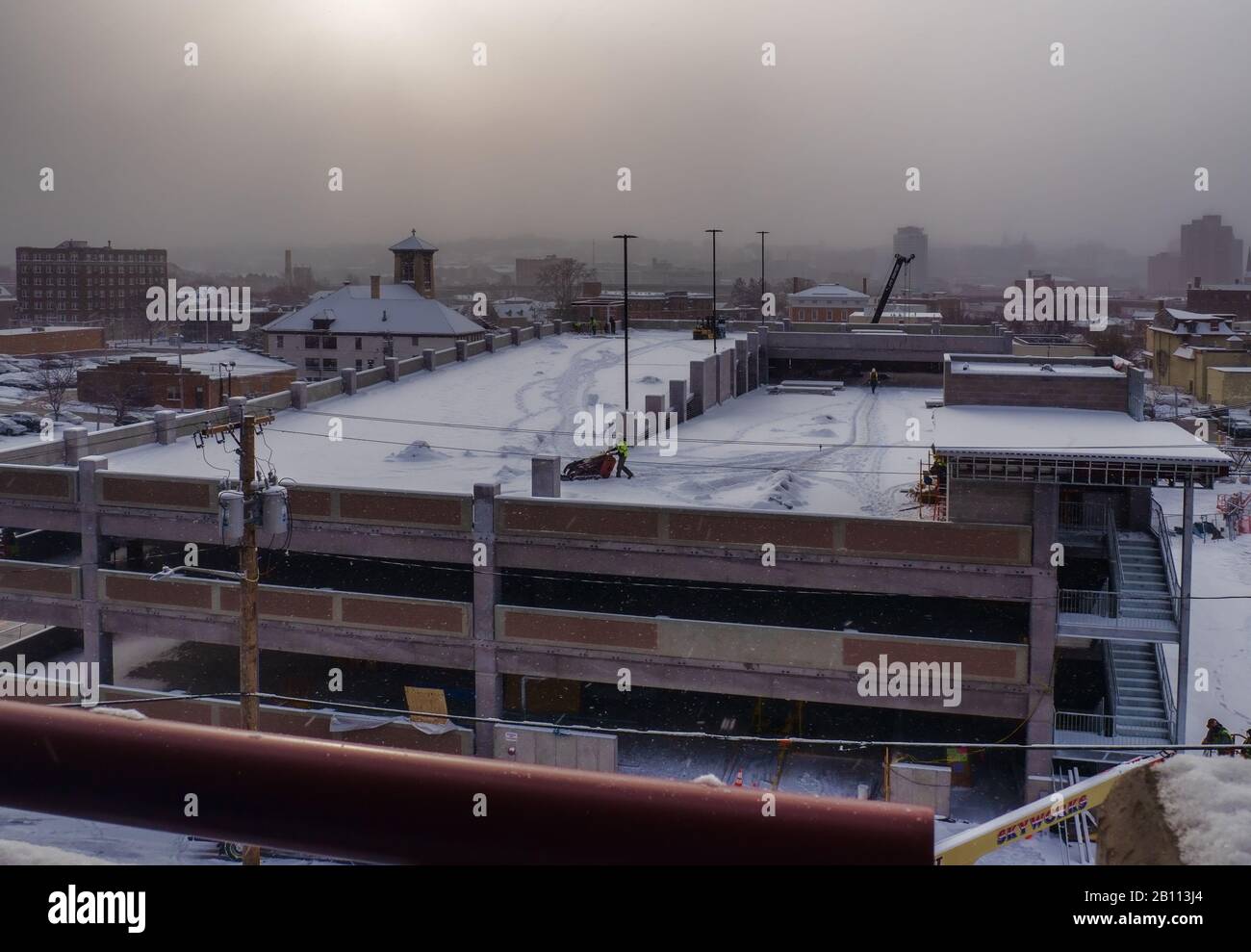 Syracuse, Nueva York, Estados Unidos. 20 De Febrero De 2020. Vista del garaje que se está construyendo para un hospital con nieve cayendo al amanecer en el lado norte de S. Foto de stock