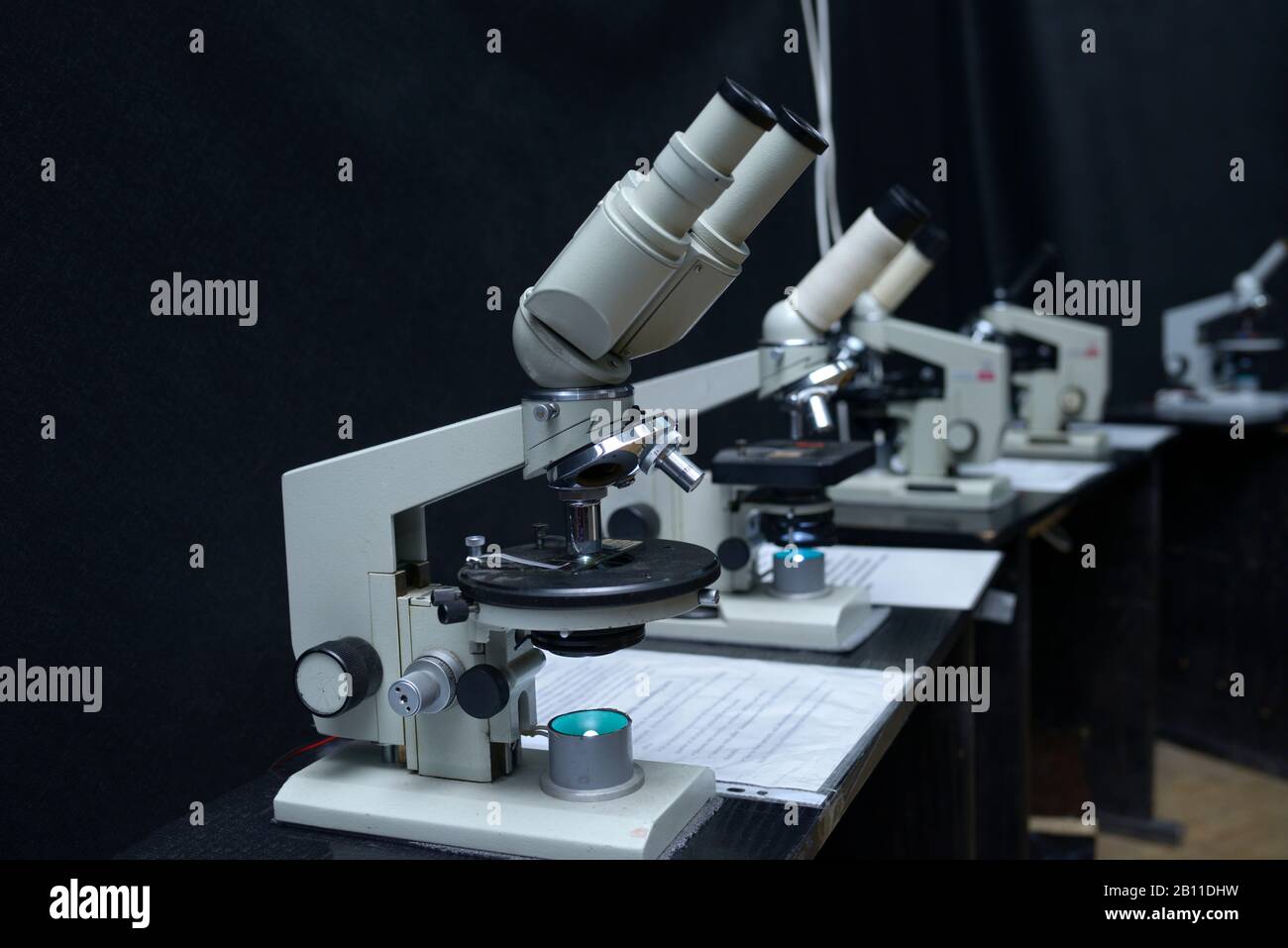 Microscopios en la mesa de trabajo del laboratorio escolar, fondo negro Foto de stock