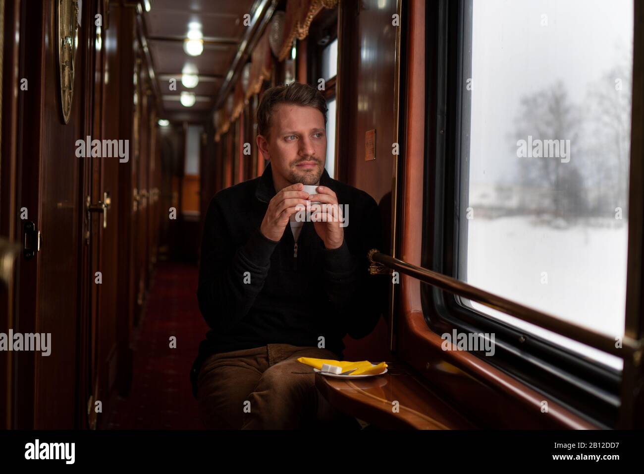Ferrocarril Transiberiano en invierno, hombre sentado en el tren mirando por la ventana, Rusia Foto de stock